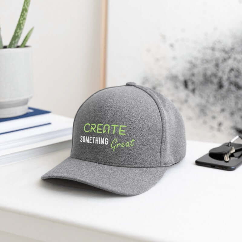 Gray cap with 'Create Something Great' text on a desk with office items.