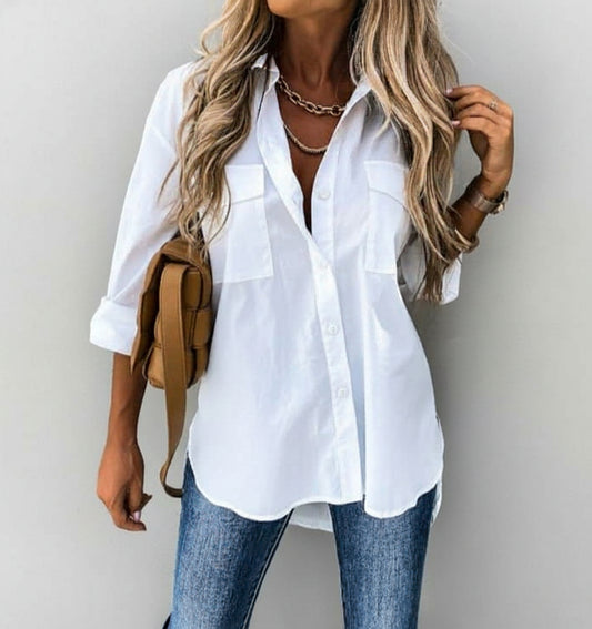 A woman wearing a white shirt and blue jeans against a gray wall