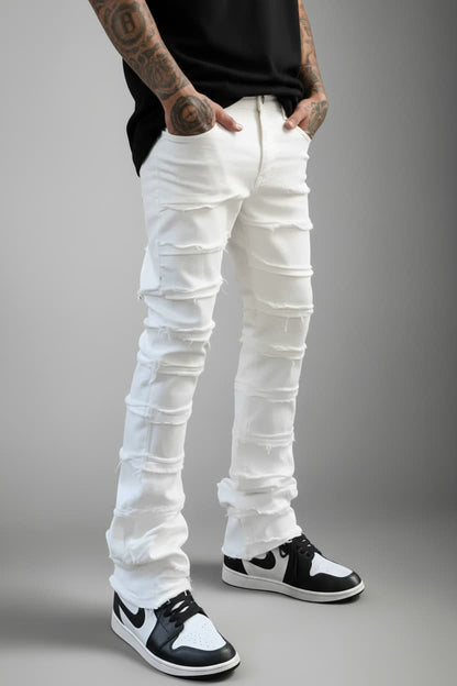 Person wearing white distressed jeans and black and white sneakers on a gray background