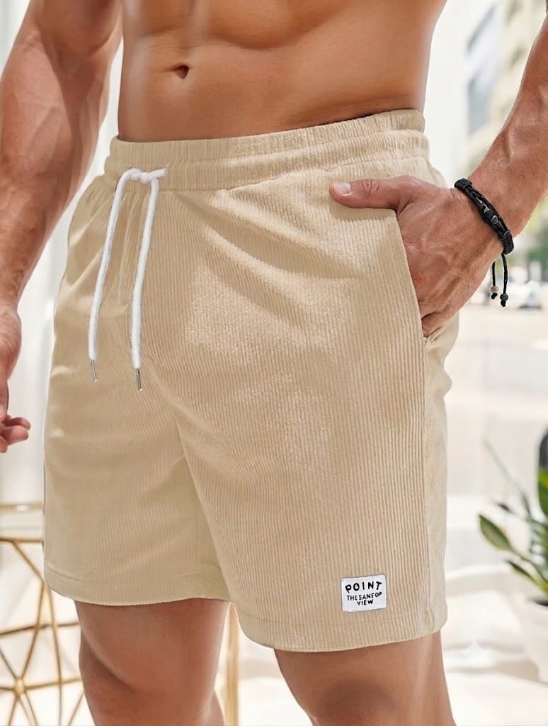 Beige textured corduroy shorts with a white drawstring and a small white patch on the lower left leg.