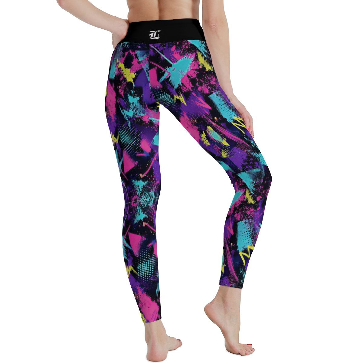 A person modeling high-waisted leggings with a black waistband and a vivid abstract print in pink, purple, teal, and yellow on a plain white background.