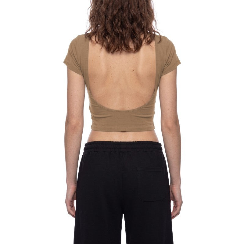 A woman shown from the back wearing a cropped taupe-brown short-sleeve top with a very large open back and black pants, against a plain white studio background.