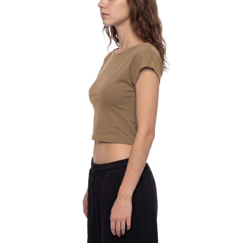A woman shown in side profile wearing a cropped short-sleeve knit top in a warm taupe-brown color, paired with black pants, against a plain white background.