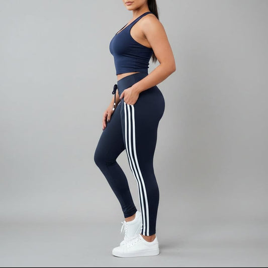 Person wearing a navy sports bra and leggings with white stripes on a gray background