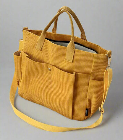 Yellow corduroy bag with multiple pockets and a shoulder strap on a gray background