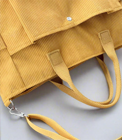 Yellow textured handbag with a strap on a light gray background